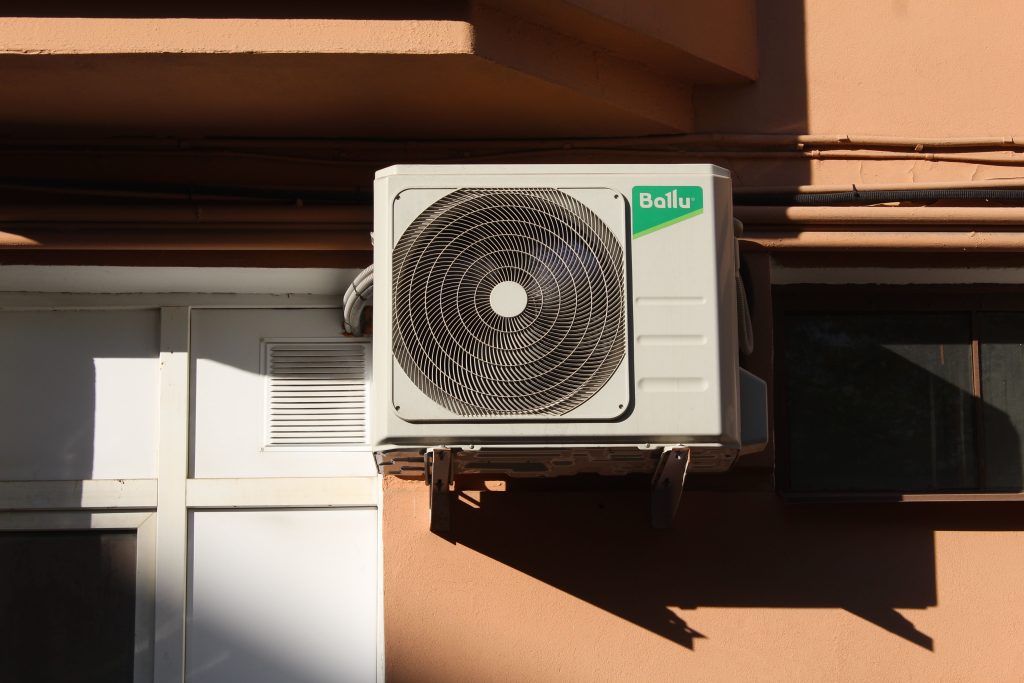 A Ballu air conditioner condenser unit mounted on a building exterior, showcasing modern HVAC technology.